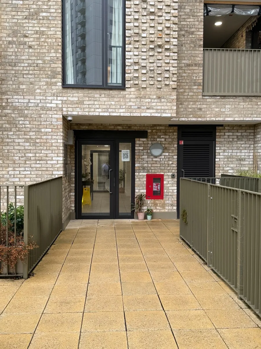 The entrance to Sonolite Court: black double glass doors at the end of a paved ramp, with a red fire box beside them.