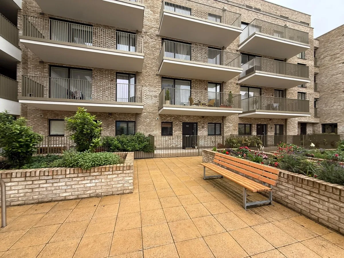 The central courtyard, with ground-floor flat front doors along the building and raised planters.
