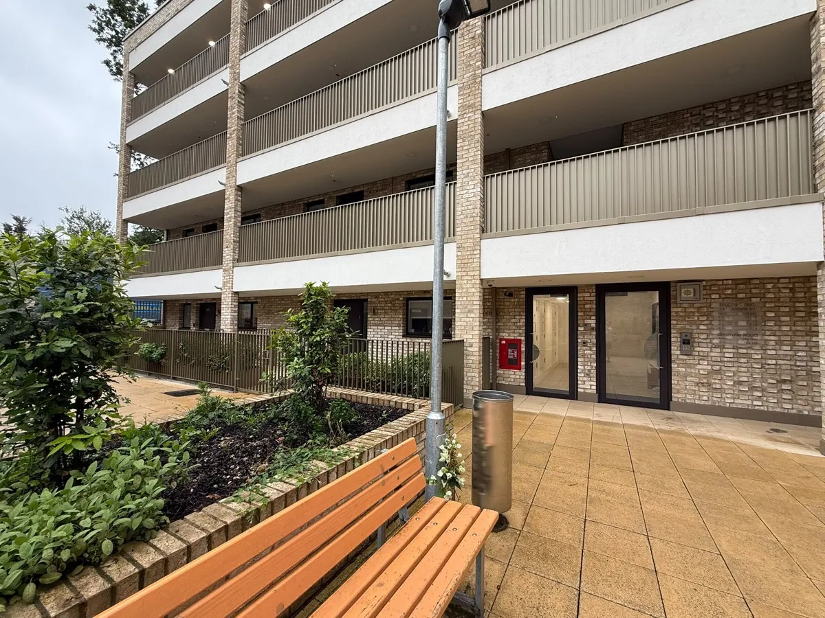 A paved path beside the building leading to a ground-floor flat entrance.